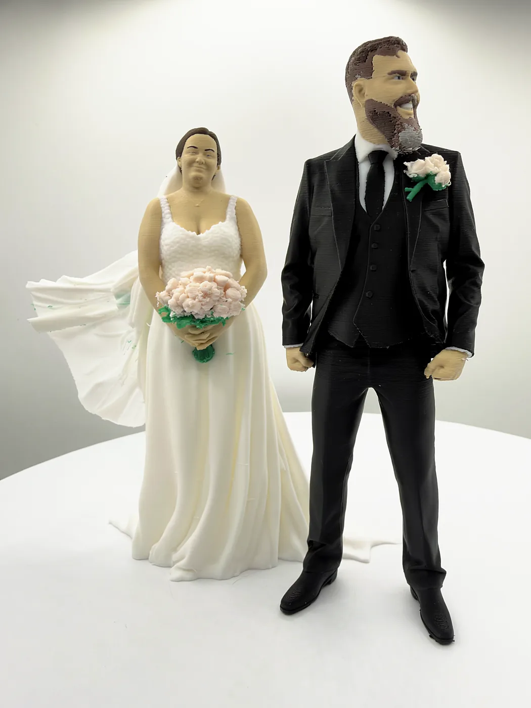 A closer view of the bride and groom figures: her bouquet held in both hands, his buttonhole on the lapel